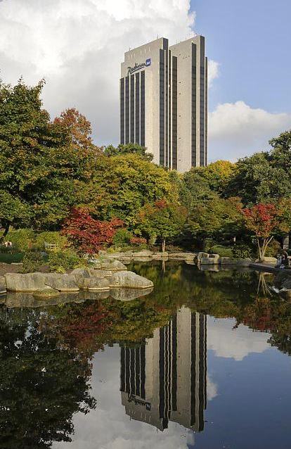 869_18985 Im Zentrum des Japanischen Gartens in den Hamburger Wallanlagen liegt ein kleinen See. Die Bltter der japanischen Zierahorne am Seeufer frben sich im Herbst leuchtend rot.Das 32 Stockwerke hohe Radisson Hotel spiegelt sich im Wasser. 