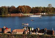 16_03811 Parkbesucher stehen an der Ziegelmauer des Bootsanlegers beim Stadtparksee in der Herbstsonne - auf dem See fahren einige Kanus sowie ein Ruderboot und Tretboot. Im Hintergrund die rotbraunen herbstlichen Bume beim Freibad Stadtparksee, dessen Saison beendet ist und schon geschlossen hat. Ein Schiff der Alsterflotte hat auf seiner Hamburger Kanalrundfahrt auch einen Abstecher in den Stadtparksee gemacht - es wird dort wenden und wieder auf den Goldbekkanal zurck fahren.  www.christoph-bellin.de