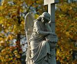 16_038161  trauernder Friedhofsengel vor gelben Herbstlaub - der Engel kniet vor einem Kreuz und hat den Kopf in die Hand gestützt.   ©www.christoph-bellin.de