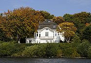 16_038162  weisse Jugendstilvilla an der Elbchaussee mit Blick auf die Elbe - die Villa steht inmitten von hohen Bäumen, die ihre rote und gelbe Herbstfärbung angenommen haben. Am Elbufer haben die Blätter der Weiden noch ein frisches Grün.   ©www.christoph-bellin.de