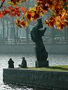 16_03816 zwei HamburgerInnen sitzen in der herbstlichen Abendsonne auf der Mauer am Ufer der Binnenalster; die Skulptur "Die Windsbraut" von Hans-Martin Ruwoldt wirft einen langen Schatten - davor das rotbraune und goldene Herbstlaub von einem Ahorn.  ©www.christoph-bellin.de