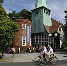 17_21484 Blick ber den Kirchenplatz zum Turm des Hasse - Hauses und der Bergedorfer Kirche St. Petri und Pauli Kirche. Bergedorfer sitzen auf Holzbnken  in der Sonne vor dem historischen Gebude - Ensemble; Fahrradfahrer fahren auf der verkehrsberuhigten Strasse. In dem Fachwerkgebude, dem frheren Organistenhaus, wurde 1699 der Rokoko Komponist Johann Adolph Hasse geboren. Der runde Klinkerturm ist erst 1836 errichtet - dort ist jetzt das Bergedorfer Touristenbro, die Bergedorf - Info eingerichtet. www.hamburg-fotograf.com