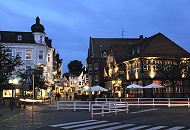 17_21486 Blick von der Alten Holstenstrasse in die Strasse Sachsentor der City Bergedorfs - die Geschfte sind in der Abenddmmerung zur "Blauen Stunde" beleuchtet. Rechts das historische Fachwerkgebude vom Gasthaus "Stadt Hamburg", das um 1550 gegrndet wurde - es befindet sich jetzt dort ein Fleischrestaurant; im Sommer knnen die Gste auf der Strasse unter Sonneschirmen sitzen und essen. www.hamburg-fotograf.com