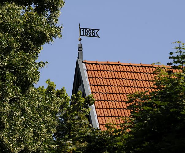 Bild Wetterfahne mit Jahreszahl - Bergedorfer Architekturfoto  Eine Wetterfahne mit der Jahreszahl 1896, dem Baujahr des Gebudes, ziert das Dach des Hauses im Villenviertel von Hamburg Bergedorf. Ende des 19.  Jahrhunderts wurde begonnen, das sogenannte Villenviertel zu bebauen -  wohlhabende Hamburger und Bergedorfer Brger lieen dort ihre reprsentativen Wohnhuser errichten. Es entstanden Stadthuser, die die unterschiedlichen Stile der Architektur ausdrckten - neben der Bauform der Grnderzeit wurde auch der Jugendstil architektonisch umgesetzt oder Wohnhuser in der Architektur der neuen Sachlichkeit gebaut