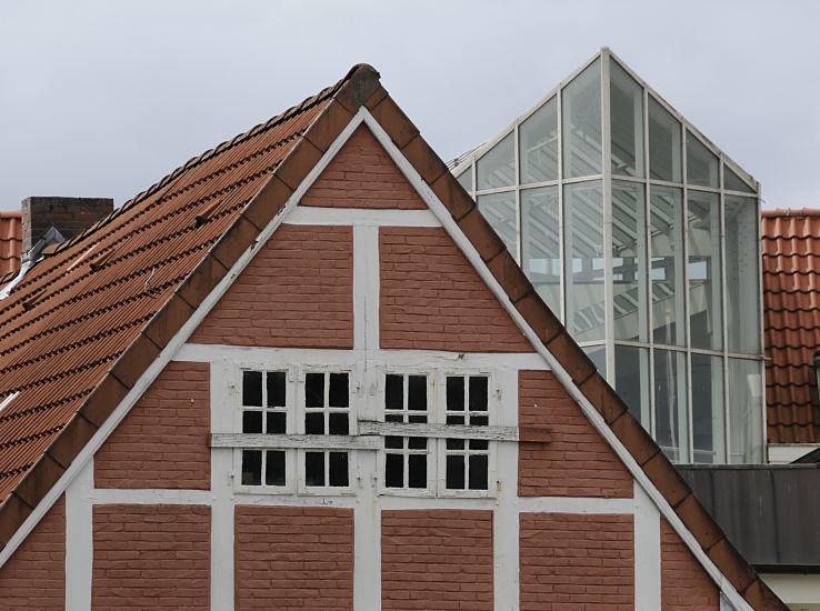 Bild der historischen und modernen Architektur in Hamburg Bergedorf   Im Vordergrund ist in der Bergedorfer City der Giebel von einem historisches Fachwerkhaus, dahinter eine moderne Glasfront eines Neubaus. 