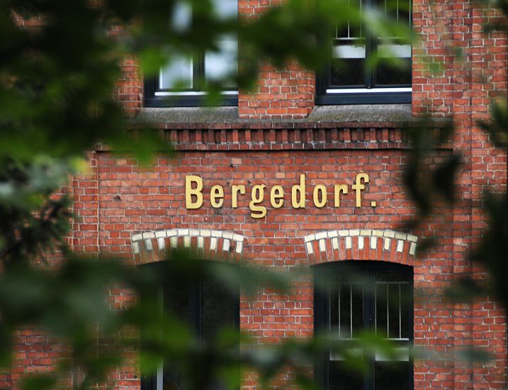 Foto der historischen Bergedorfer  Industriearchitektur - Grnderzeit.  An dem historischen Industriegebude ist in goldenen Buchstaben der Name Bergedorfs zu erkennen. ber den Fenstern wird mit hellen Steinen ein Dekor erstellt, dass sich von der roten Backsteinfront abhebt. 