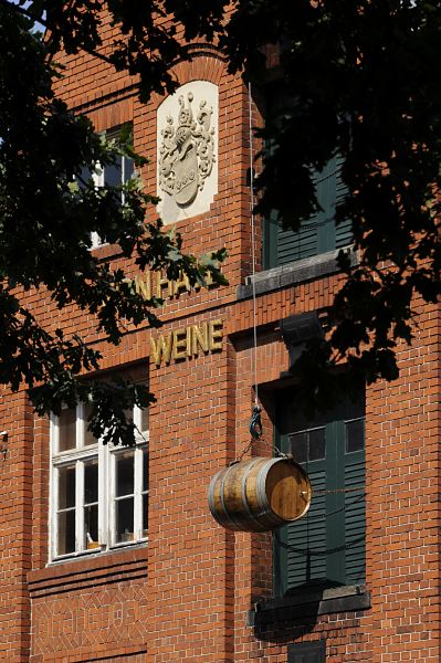 Fotografie Speichergebäude, Weinfass Historisches Speichergebäude einer Weinhandlung in Hamburg Bergedorf. Über der Inschrift ist ein Wappen eingelassen; vor einer der Speichertüren hängt an Seil und Haken einer Dachwinde ein Weinfass als Dekoration.
