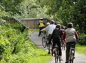 17_21555 Eine Familie macht auf dem Billewanderweg eine Fahrradtour. Eine Holzbrücke führt die Fahrradfahrer und Fahrradfahrerinnen über den Hamburger Fluss.