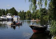 17_21584 Zwei Kanus fahren bei strahlendem Hamburger Sommerwetter auf der Dove-Elbe - lks. linken liegen Motoryachten am Bootssteg eines Vierlnder Yachthafens. Im Vordergrund am Steg des Hotels Vierlandentor hat das Tuckerboot HUMMEL festgemacht - ein dicker umlaufenden Tampen / Seil dient als Scheuerschutz. Die Tuckerboote waren offene Arbeitsbarkassen im Hamburger Hafen; sie brachten als Zubringerboote u.a. auch Hafenarbeiter an ihren Arbeitsplatz.  www.hamburg-fotograf.com