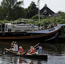 17_21585 Eine Familie paddeln in einem Kanu auf der Dove-Elbe - die Kinder tragen zur Sicherheit Schwimmwesten. Am Ufer liegt ein Segelschiff, das zum Hausboot umgebaut wurde, dahinter ein strohgedecktes Wohnhaus.  ©www.hamburg-fotograf.com