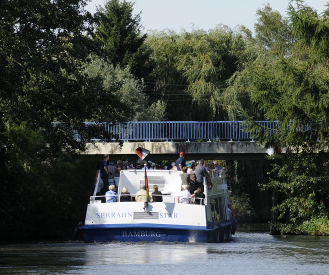 Das Bergedorfer Touristenschiff SERRAHN STAR hat auf seiner Vierlanden Tour vor dem Neuengammer Stichanal gewendet und passiert gerade die BLAUE BRCKE in Hamburg Curslack, Bezirk Bergedorf. Die Schiffe der Bergedorfer Schifffahrtslinie, die u.a. die Vierlnder Touren anbieten sind sehr flach gebaut, damit sie in der Lage sind, die niedrigen Brcken auf der Strecke zu passieren.  Hamburger Bilder - Fahrgastschiff mit Bergedorf Touristen bei Curslack.