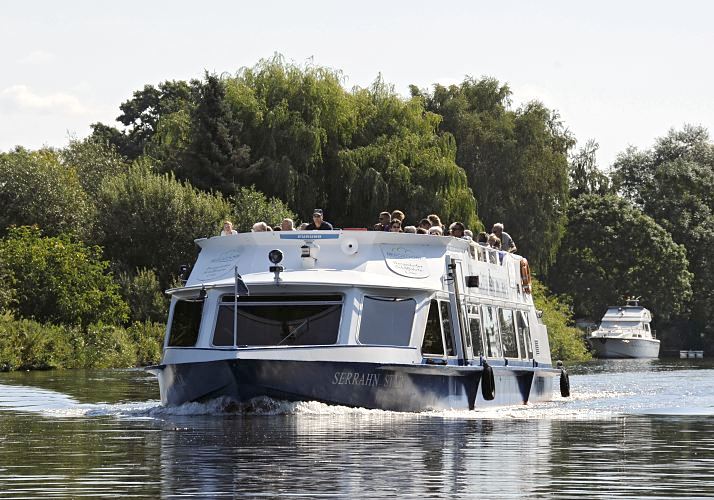 Bilder aus den Hamburger Bezirken - Bergedorfer Dove - Elbe, Ausflugsschiff   Eine Ausflugsbarkasse fhrt mit Bergedorf-Touristen an Bord auf seiner Rundfahrt durch die Vierlande und Marschlande auf der Doveelbe. Auf dem Fahrgastschiff SERRAHN STAR der Bergedorfer Schifffahrtslinie sitzen die Fahrgste auf dem Sonnendeck und geniessen den Ausblick bei Hamburger Sommerwetter. Im Hintergrund eine Motoryacht die am Bootssteg liegt.