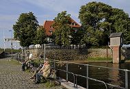 17_21619 Blick ber die Kaianlage der Zollenspieker Fhre zum Fhrhaus, das zwischen den Bumen versteckt ist. Der Weg ist mit Kopfstein gepflastert - rechts das Pegelhaus; Mwen schwimmen auf dem Wasser. www.hamburg-fotograf.com