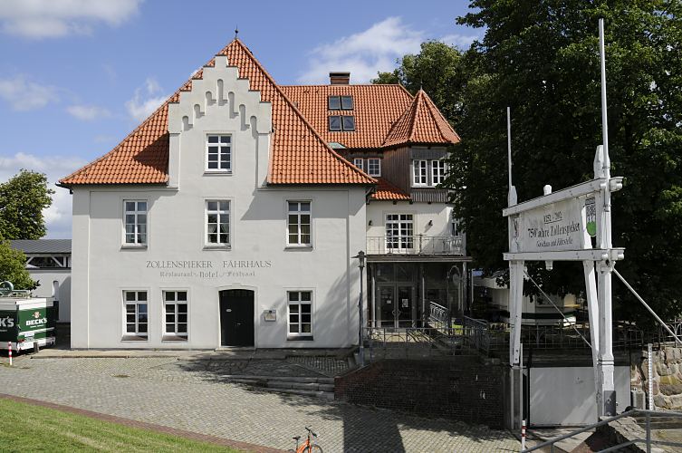 Architektur des historischen Zollenspieker Fhrhaus - der Zollenspieker wurde erstmals Mitte des 13. Jhd. als Zollstation erwhnt. Das Gebudes des Zoll- und Fhrhaus wurde ursprnglich ca. 1460 errichtet - eine wehrhafte Neuanlage wurde dann um 1620 gebaut. Die Wartezeit auf die Fhre nach Hoopte konnte in dem angegliederten Gaststtte verkrzt werden. Ende des 19. Jhd. entwickelte sich das Zollenspieker Fhrhaus zum beliebten Ausflugsziel fr die Hamburger Bevlkerung. Rechts ber den Torpfosten ein Hinweisschild, dass der Zollenspieker schon mehr als 750 Jahre als Gasthaus und Fhrstelle existiert.  Hamburger Architektur Fotografie - Gebude des Zollenspieker Fhrhaus, Kirchwerder. 