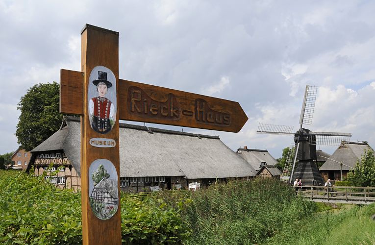 Bild vom geschnitzten Holzschild Freilichtmuseum Rieck-Haus, Bauernhaus - Windmhle  Das handgeschnitzte Holzschild weist fr die Besucher den Weg zum Rieck Haus, dem Freilichtmuseum in den Hamburger Vierlanden; die Anlage ist seit 1954 eine Aussenstelle des Altonaer Museums. Das Rieckhaus in Hamburg Curslack wurde ca. 1550 errichtet und ist ein typisches niederdeutsches Fachhallenhaus - es soll zu den ltesten Profanbauten Hamburgs gehren