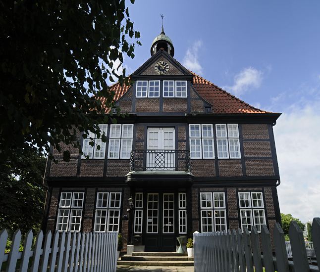 Eingang des Glockenhaus Billwerder; das zweistckige Fachwerkhaus wurde ursprnglich als Bauernhaus um 1600 errichtet und um 1780 zum Landhaus eines Hamburger Brgers umgebaut. ber dem Balkon befindet sich der Glocken-Dachreiter, nach dem das Haus benannt worden ist. Ein weiss gestrichener Staketenzaun grenzt den Weg zum Eingang des Glockenhauses ab  Bilder aus dem Hamburger Bezirk Bergedorf - Glockenhaus Billwerder