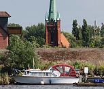 17_21647 Der Kirchturm der St. Nikolaikirche in Hamburg Moorfleet wurde 1885 errichtet. Im Vordergrund ein Sport- boot mit herunter geklapptem Verdeck und Bootsstege im Holzhafen; dahinter ist der Deich zu erkennen  ©www.hamburg-fotograf.com
