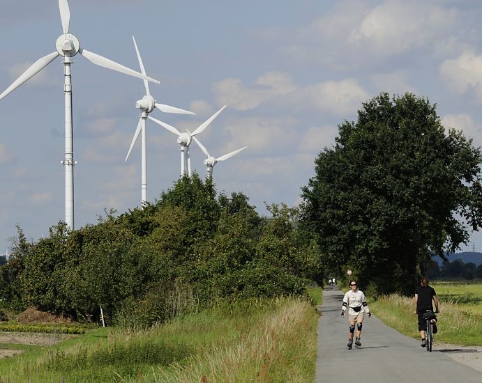 Windkraftanlagen und Rotorbltter in den Hamburger Vier- und Marschlanden. In diesem Bergedorfer Bezirk wurde schon 1991 Hamburgs erste Windenergieanlage errichtet. Die schnurgerade asphaltierte Strasse ist die Trasse der ehemaligen Vierlnder Marschenbahn; die Bahnlinie wurde 1961 endgltig eingestellt. Jetzt wird die Strecke gerne von Radfahrern und Rollerskater genutzt.  Hamburg Fotos - Windkraftanlagen in den Vier- und Marschlanden, Marschbahn  