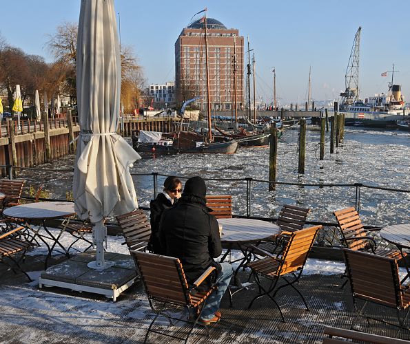 Motive vom Hamburger Leben im Winter - Gste im Elbcaf, Auenterrasse. 008_22738 Bei sonnigem Hamburger Winterwetter sitzen Gste im Caf am Museumshafen Oevelgoenne. Im Hintergrund das ehem. Khlhaus von Hamburg Neumhlen, das jetzt als Seniorenresidenz seinen Einwohnern einen interessanten Blick ber Elbe bietet..