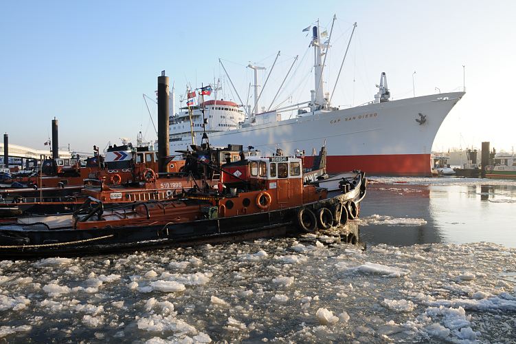 009_22739 Schlepper liegen bei den Landungsbrcken an den Dalben. Eisschollen treiben auf dem Wasser der Elbe. Im Hintergrund das Museumsschiff CAP SAN DIEGO. www.hamburg- fotograf.com   Wintermotive aus Hamburg - Museumsschiff CAP SAN DIEGO, Schlepper im Eis. 