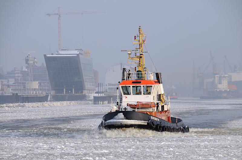 Hamburger Winterimpressionen - Schlepper werden als Eisbrecher bei Eisgang auf der Elbe eingesetzt. 03_5410 Der Schlepper BUGSIER 18 fhrt durch das dichte Treibeis auf der Elbe;  links die futuristische Architektur des Brogebude Dockland - rechts die Werftanlagen von Blohm + Voss.