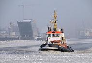 03_5410 Der Schlepper BUGSIER 18 fhrt durch das dichte Treibeis auf der Elbe;  links die futuristische Architektur des Brogebude Dockland - rechts die Werftanlagen von Blohm + Voss. 