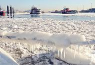 05_5688 Frost und Eis in Hamburg - ein Schiffstau am Anleger Övelgönne ist mit dickem Eis und Eiszapfen bedeckt, die in der Wintersonne glänzen. Zwei Hafenfähren fahren durch das dichte Treibeis auf der Elbe. Fotos vom Hamburger Winter - vereistes Schiffstau und Hafenfähren auf der Elbe.