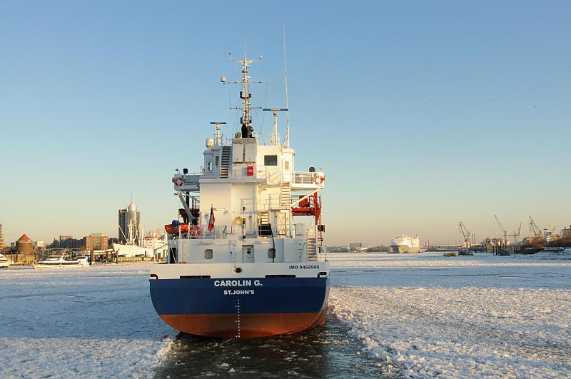 13_5844 Der Container Feeder CAROLIN G. luft durch das dichte Treibeis in den Hamburger Hafen ein. Links im Hintergrund der Broturm am Kehrwieder der Speicherstadt, davor das Museumsschiff CAP SAN DIEGO an der berseebrcke. Winter in der Hafenstadt Hamburg -  Frachtschiff luft in den Hamburger Hafen ein.