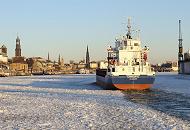 14_5837 Die Elbe vor den andungsbrcken ist dicht mit Treibeis bedeckt. Das Frachtschiff CAROLIN G. bahnt sich seinen Weg durch die Eisschollen, um seinen Liegeplatz im Hamburger Hafen zu erreichen. Im Hintergrund das Hamburger Panorama mit den Sandsteingebuden der Landungsbrcken, dem kupfergedeckten Kuppelgebude des Alten Elbtunnels und den Kirchtrmen von vier der fnf Hamburger Hauptkirchen. Panorama der Hansestadt Hamburg im Winter -  Kirchtrme der Hamburger Hauptkirchen.