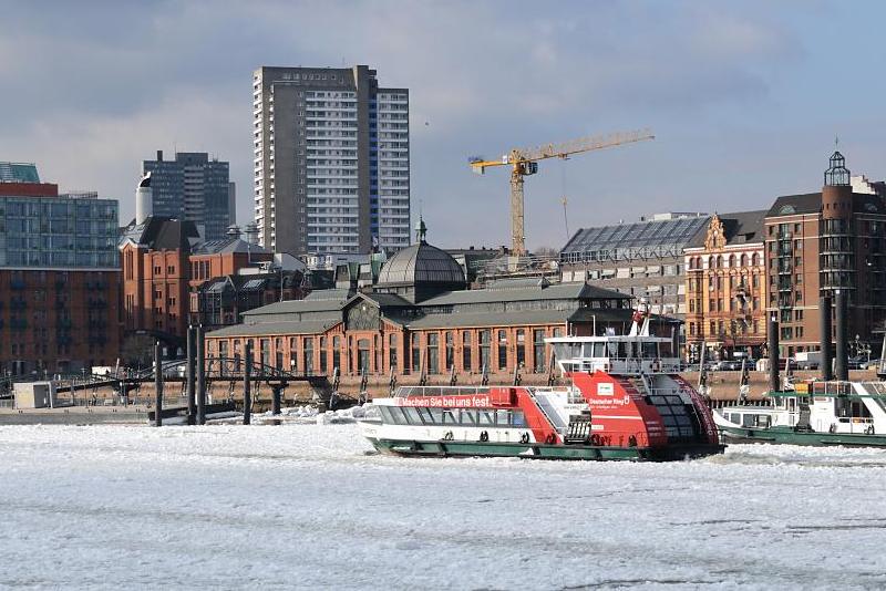 1810 Eine Hafenfhre kommt von den St. Pauli Landungsbrcken und fhrt Richtung Anleger Fischmarkt / Altonaer Fischauktionshalle; die Elbe ist dicht mit Eis bedeckt; das Fhrschiff bahnt sich seinen Weg durch die Eisschollen. Hinter dem histoirschen Auktionsgebude Kontorhuser an der Grossen Elbstrasse.  