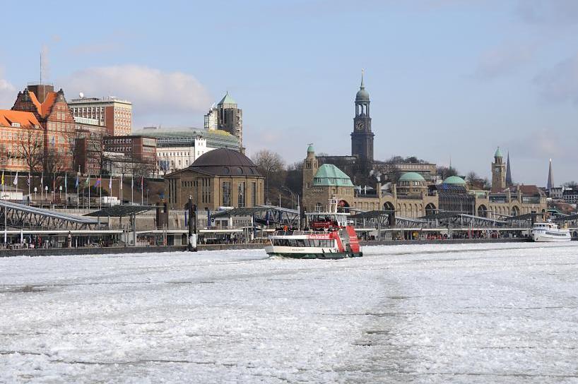 1814 Eine Elbfhre hat von den St. Pauli Landungsbrcken abgelegt und fhrt Richtung Altona - die Fahrrinne des Schiffs wird rasch wieder von den Eisschollen geschlossen, die das Elbwasser dicht bedecken. Im Hintergrund die historischen Gebude vom Elbtunnel und den Landungsbrcken sowie Kirchtrme der Hansestadt.