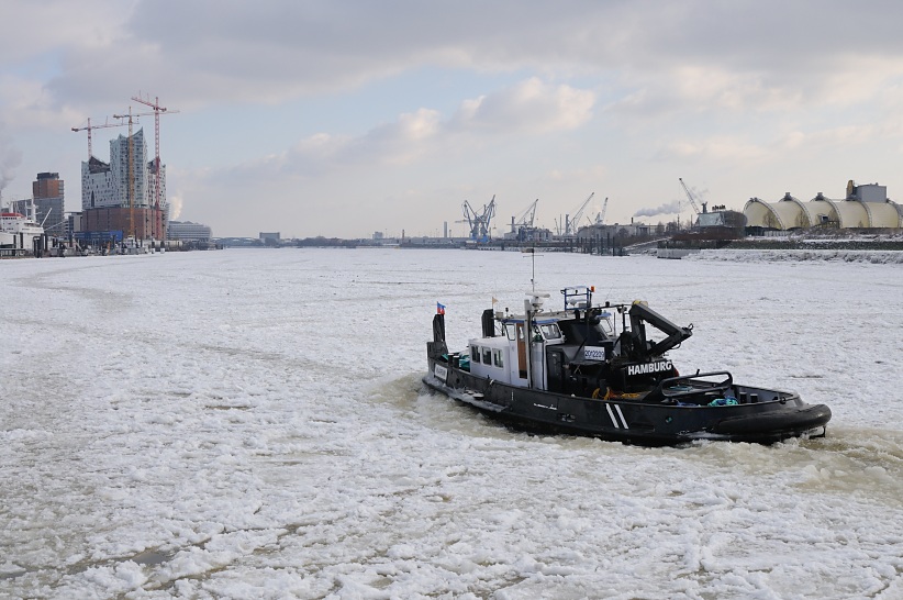 1815 Ein Schubschiff bahnt sich seinen Weg durch das dichte Eis auf der Elbe im Hamburger Hafen - die Arbeitsschiffe werden als Eisbrecher eingesetzt, um das Eis in Bewegung zu halten. Im Hintergrund rechts das Theaterzelt vom "Knig der Lwen" und lks. die Baustelle der Elbphilharmonie.