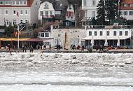 1891 Winterspaziergang an der Elbe - die SpaziergngerInnen machen an der Strandperle eine Pause und blicken auf die vereiste Elbe. Es ist Niedrigwasser und das Eis hat sich am Elbufer hoch abgelagert. Im Hintergrund Wohnhuser von Hamburg Oevelgnne. 