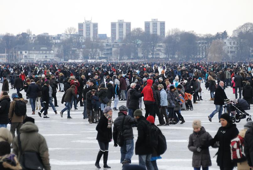 2011 Dicht gedrngt genieen die HamburgerInnen die einmalige Atmosphre auf der zugefrorenen Auenalster - sie stehen auf dem Eis und klnen oder gehen mit ihren Kinder spazieren. Im Hintergrund Hochhuser in Hamburg Winterhude.