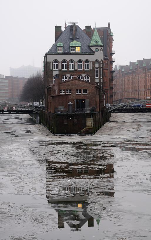 2067 Blick auf das Wasserschlsschen in der Hamburger Speicherstadt an einem grauen Wintertag. Das Fleet ist mit Eisschollen bedeckt, das historische Gebude spiegelt sich im Wasser.  