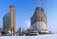 22_5304 Die Elbfhre HAFENCITY verlsst den Anleger am Sandtor; links neben der Einfahrt zum Sandtorhafen der moderne Brokomplex am Kehrwieder und rechts die Hamburger Grossbaustelle der zuknftigen Elbphilharmonie mit den weit sichtbaren Baukrnen.  Hamburg-Motive: die Baustelle der Elbphilharmonie im Winter; Hafenfhre.