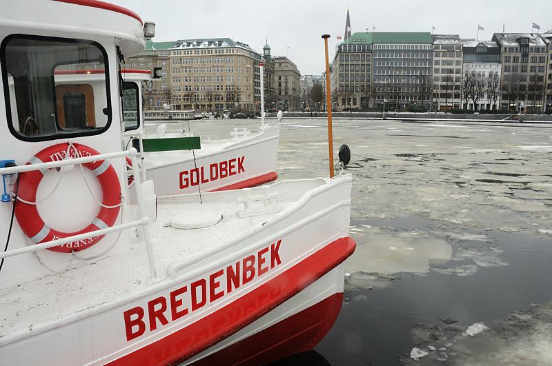 29_3_5122 Die Alsterschiffe Goldbek und Bredenbek liegen am Jungfernstiegs und haben Winterpause; die Binnenalster ist mit Eisschollen bedeckt. Im Hintergrund der Ballindamm und das Alstertor. Hamburger Winterimpressionen - Alsterschiffe am Ponton in der Binnenalster.