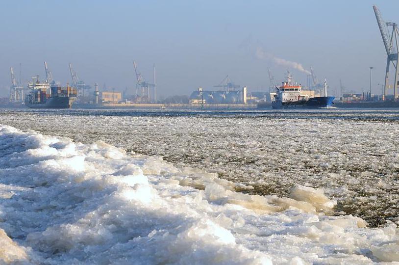 3133 Schiffsverkehr zwischen Eisschollen auf der Elbe - zwei Frachtschiffe laufen aus dem Hamburger Hafen aus; die Elbe ist dicht mit Eis bedeckt - im Hintergrund die Mndung der Sderelbe / Khlbrand in die Norderelbe. Der Elbstrand ist dicht mit einer Eisschicht bedeckt.