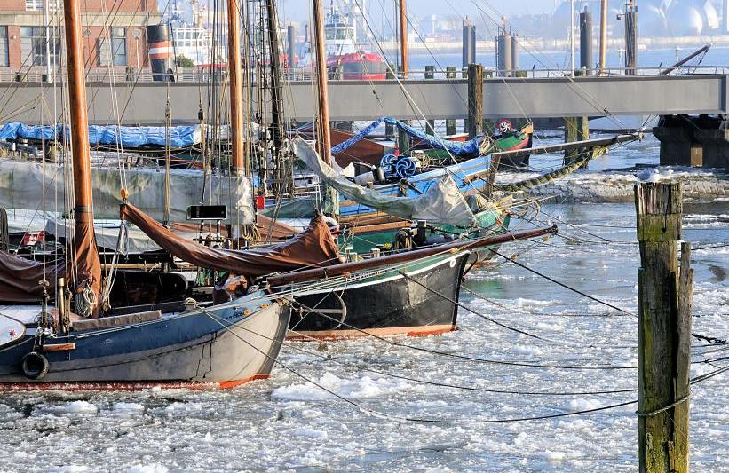 3150 Die historischen Schiffskutter liegen im Eis vom Museumshafen Oevelgnne - die historischen Schiffe sind an Dalben vertut. Im Hintergrund die Wassertreppe zum Schiffsanleger und Schlepper am Anleger Hamburg Neumhlen. www.hamburg- fotograf.com