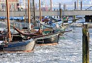 3150 Die historischen Schiffskutter liegen im Eis vom Museumshafen Oevelgnne - die historischen Schiffe sind an Dalben vertut. Im Hintergrund die Wassertreppe zum Schiffsanleger und Schlepper am Anleger Hamburg Neumhlen.