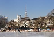 37_5514 Blauer Winterhimmel ber Hamburg - die Aussenalster ist zugefroren. Hamburger und Hamburgerinnen nutzen das schne Winterwetter und gehen auch mit Kinderwagen auf dem Eis spazieren. Andere laufen Schlittschuh auf Hamburgs groem Binnensee. Im Hintergrund historische Hamburger Architektur an der Strasse ALSTERUFER und der Fernsehturm, der zwar den offiziellen Namen Heinrich Hertz Turm hat, aber zumeist Telemichel genannt wird. Hamburger Winterfotos - die zugefrorene Aussenalster mit Spaziergngerinnen auf dem Eis. 