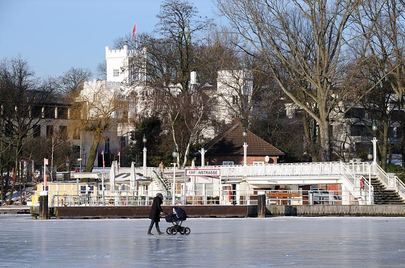 39_5518 Eine Mutter geht auf der zugefrorenen Alster vor dem Schiffsanleger RABENSTRASSE spazieren - sie schiebt ihren Kinderwagen ber das Eis. Hamburger Wintermotive - Schiffsanleger Rabenstrasse, zugefrorene Alster.