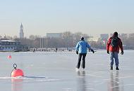 42_5592 Ein Paar nutzt den sonnigen Wintertag und läuft Schlittschuh auf der Aussenalster - die Bojen vor einer Segelschule sind im dicken Eis festgefroren. Hamburg im Winter - Eislaufen auf der zugefrorenen Aussenalster. 