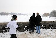 52_6076 Von der Krugkoppelbrcke hat man einen weiten Blick ber die weie, zugefrorene Alster - die Hamburger nutzen das Wintereis, um quer ber die Alster in die Hamburger Innenstadt zu spazieren. Andere joggen an Land durch den Schnee die 7,5 km um Alster herum. Aufnahmen von Hamburg im Winter - Blick von der Krugkoppelbrcke auf die Alster, Joggerin. 