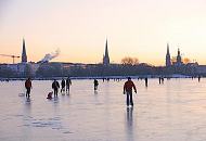 57_5906 Vor dem Hamburg-Panorama mit den markanten Kirchtrmen berqueren die Hamburger auf dem Eis der Aussenalster den 156 ha groen Hamburger Binnensee. Offiziell wird die Alster erst von der Behrde freigegeben, wenn das Eis eine Strke von 20cm hat, aber viele Hamburger laufen schon vorher z.B. mit ihren Schlittschuhen oder Schlitten ber das Eis.  Bilder vom winterlichen Hamburg - Alstervergngen bei Minustemperaturen auf der Aussenalster.