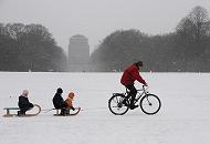 64_5069 Der Hamburger Stadtpark ist eingeschneit. Ein Vater zieht mit seinem Fahrrad die zwei Schlitten seiner Kinder durch den Schnee über die große Wiese. Bilder vom Winter in der Hansestadt Hamburg - Winterfreuden im Hamburger Stadtpark.