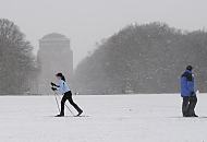 65_5059 Die groe Wiese im Zentrum des Stadtparks ist zugeschneit. Eine Skilangluferin fhrt durch den winterlichen Stadtpark, whrend ein Spaziergnger dick verpackt durch das Schneetreiben stapft.  Im Hintergrund das Hamburger Planetariums. Der ehemalige Wasserturm wird seit 1930 als Planetarium genutzt. Bilder vom Winter in der Hansestadt Hamburg - Schneetreiben und Skilanglauf im Stadtpark.