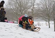 69_5027 Im dichten Schneetreiben lassen sich die Kinder ihren Spass nicht nehmen, einen kleinen Hgel im Hamburger Stadtpark herunter zu rodeln. Im Hintergrund der Spielplatz und das eingeschneite Planschbecken. Fotos von Hamburg im Winter - Kinder fahren Schlitten im Stadtpark.