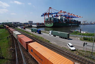 011_15761 Blick ber den Waltershofer Damm zum Eurogate Terminal - ein beladener Container Carrier liegt am Kai - alle Containerbrcken sind herunter gefahren und entladen das Schiff. Im Vordergrund ein langer Containerzug und auf der Strasse Lastwagen mit ihrer Containerladung.