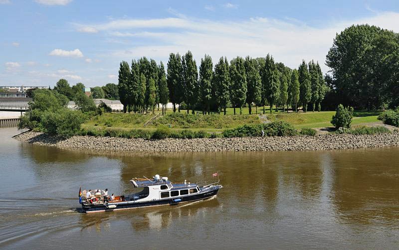 01127_3913 JEin Sportboot / Motorboot kommt vom Oberhafenkanal und fhrt in die Norderelbe ein - im Hintergrund der Elbpark Entenwerder mit den in einer Rundung 2007 bei der Gestaltung der Grnanlage neu angegepflanzten Pappeln. Das Ufer ist mit Steinen gegen die Strmung gesichert; lks. die Einfahrt zum Haken.